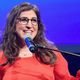 Actor and host Mayim Bialik smiling and speaking into a microphone.